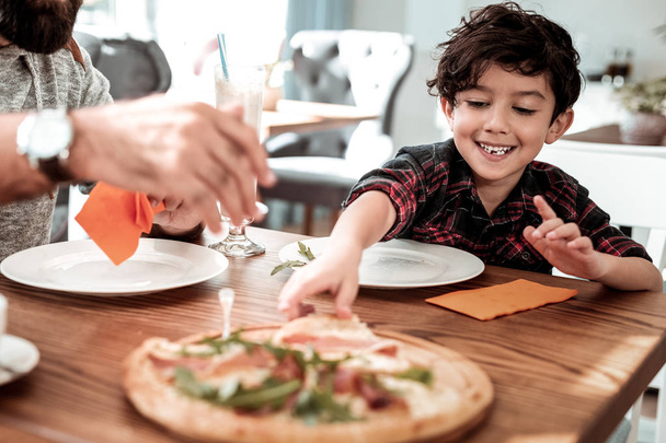 Hijo sosteniendo pedazo de pizza con tocino pasar fin de semana con el padre
 - Foto, Imagen