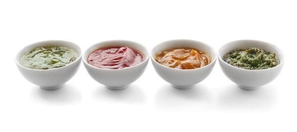 Diferentes salsas sabrosas en cuencos sobre fondo blanco
 - Foto, Imagen
