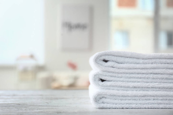 Folded white towels on light table indoors - Фото, изображение