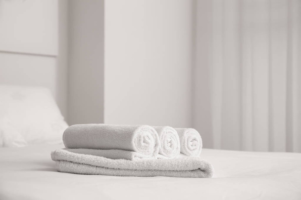 Белые мягкие полотенца на кровати в помещении
 - Фото, изображение