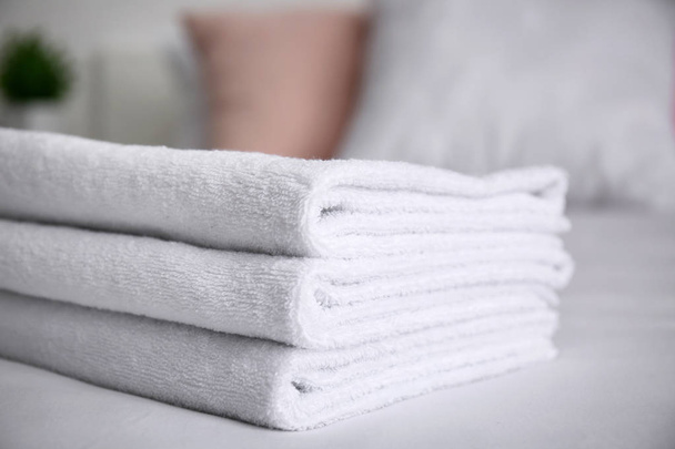 Складные белые полотенца на кровати в помещении, крупным планом
 - Фото, изображение