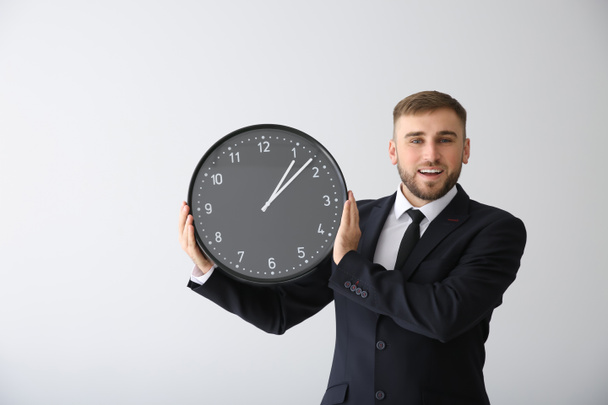 Businessman with clock on light background - Фото, зображення
