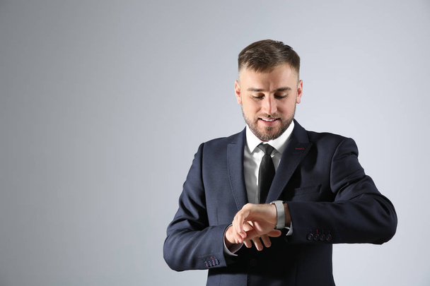 Homme d'affaires regardant sa montre sur fond clair
 - Photo, image