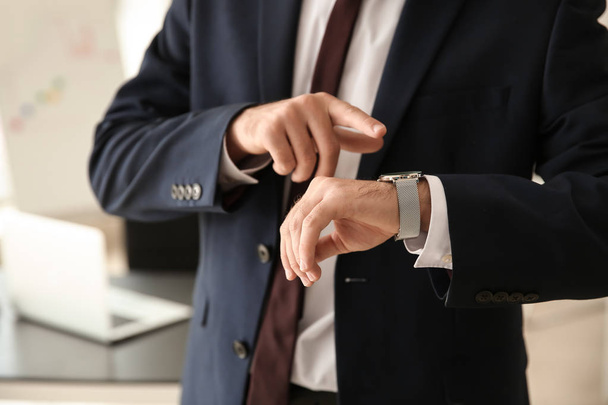 Businessman looking at his watch in office, closeup - Photo, Image