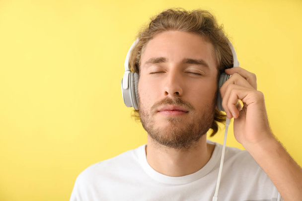 Handsome man listening to music on color background - 写真・画像