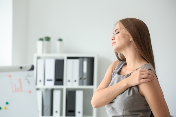 Jeune femme souffrant de douleurs à l'épaule sur le lieu de travail
 - Photo, image