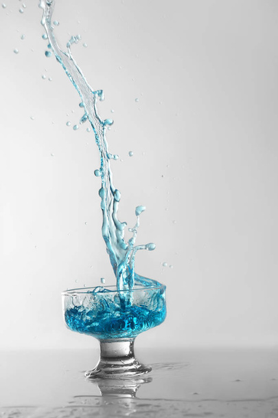Glass of blue wine with splashes on white background - Фото, изображение