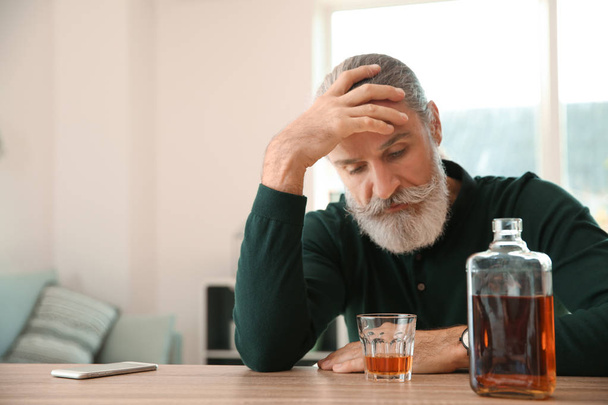 Depressed senior man drinking whiskey at home - Photo, Image