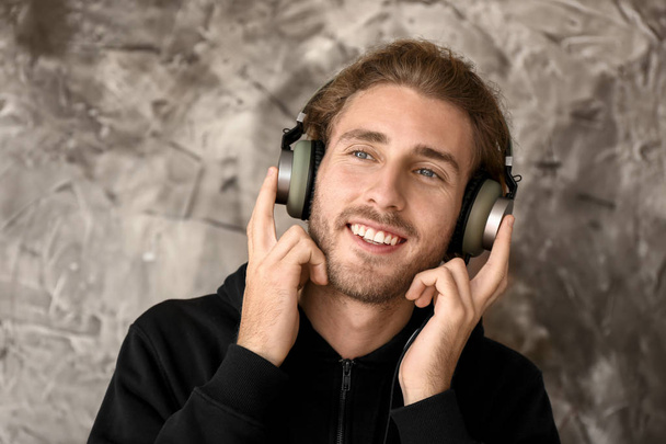 Young man listening to music on grunge background - Photo, Image