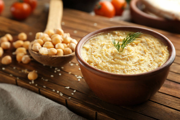 Bowl with tasty hummus on wooden board, closeup - Foto, imagen