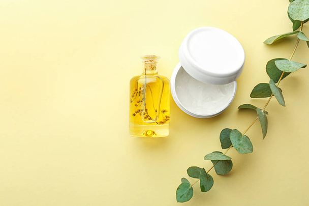 Cream and bottle of eucalyptus essential oil on color background - Photo, Image