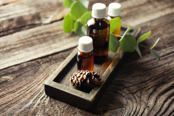 Bottles of eucalyptus essential oil on wooden background - Фото, изображение