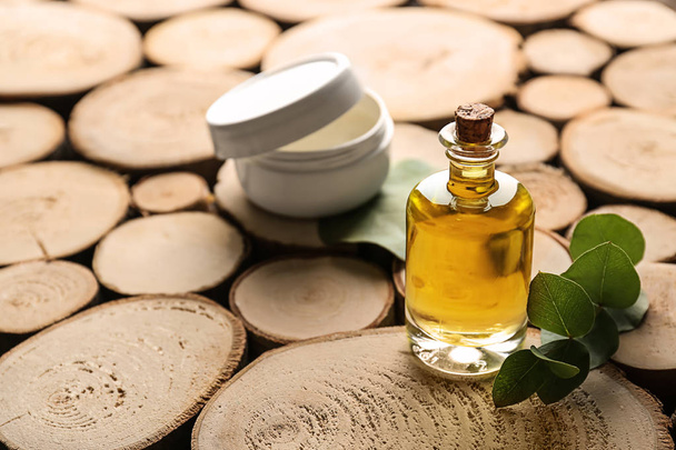 Garrafa de óleo essencial de eucalipto e frasco com creme sobre fundo de madeira
 - Foto, Imagem