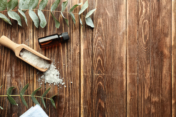 Bottle of eucalyptus essential oil and scoop with sea salt on wooden table - Valokuva, kuva