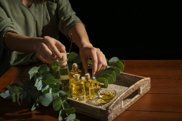 Женщина берет с подноса бутылки эфирного масла эвкалипта
 - Фото, изображение