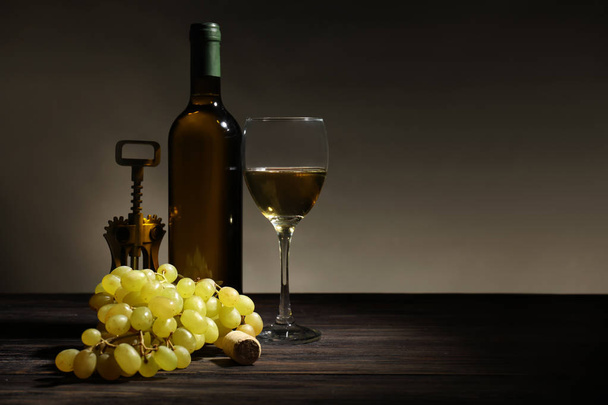 Bottle of wine, glass and corkscrew on dark background - Fotoğraf, Görsel