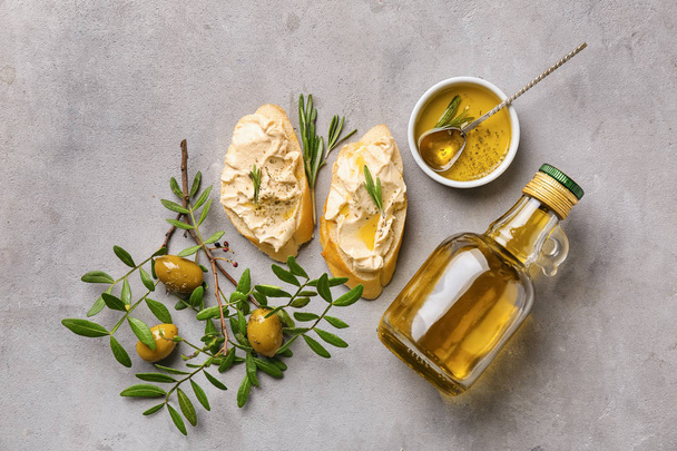 Komposition mit einer Flasche Olivenöl und Brotstücken auf grauem Hintergrund - Foto, Bild