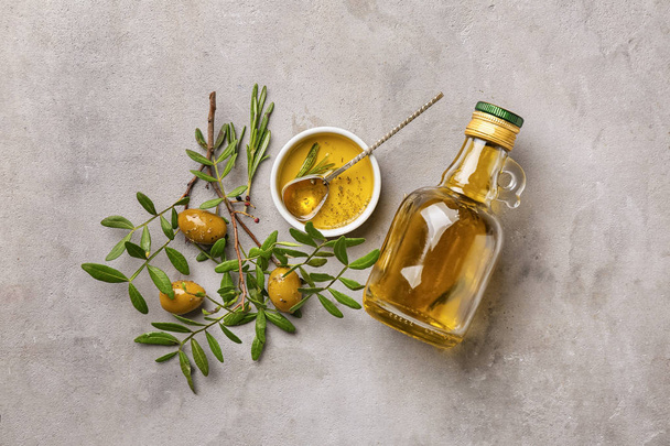 Bottle of oil with olives on grey background - Photo, Image