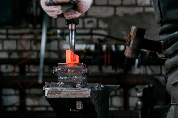 Espacio de trabajo del herrero. Herrero trabajando con metal rojo caliente en yunque en una fragua
 - Foto, imagen