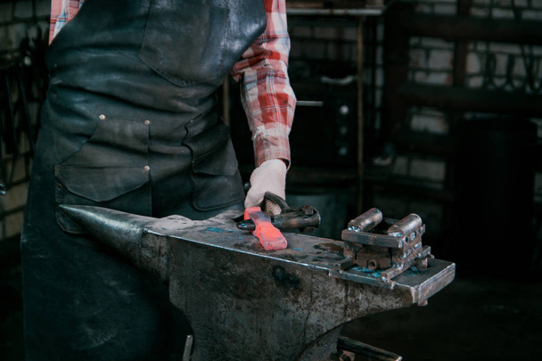 鍛冶屋の鍛造にアンビルで新しいハンマーの赤いホット金属ワークピースでの作業 - 写真・画像