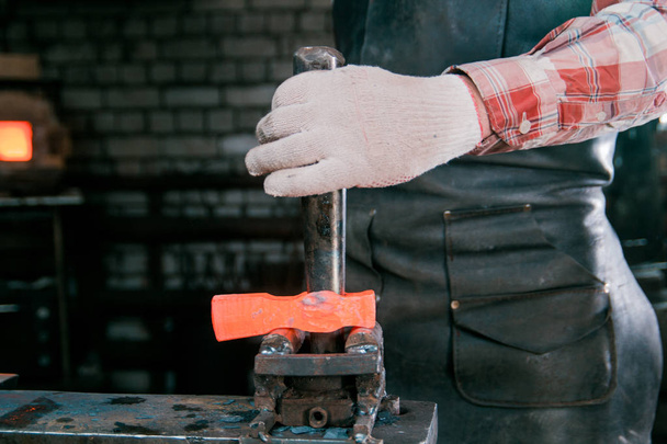 Espace de travail du forgeron. Forgeron travaillant avec une pièce en métal chaud rouge de nouveau marteau à l'enclume dans une forge. Faire le trou
 - Photo, image