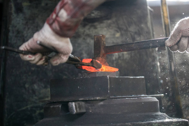 Forgeron et enclume. Forgeron travaillant avec une pièce de métal chaud rouge de nouvelle hache sur l'enclume à la forge
 - Photo, image
