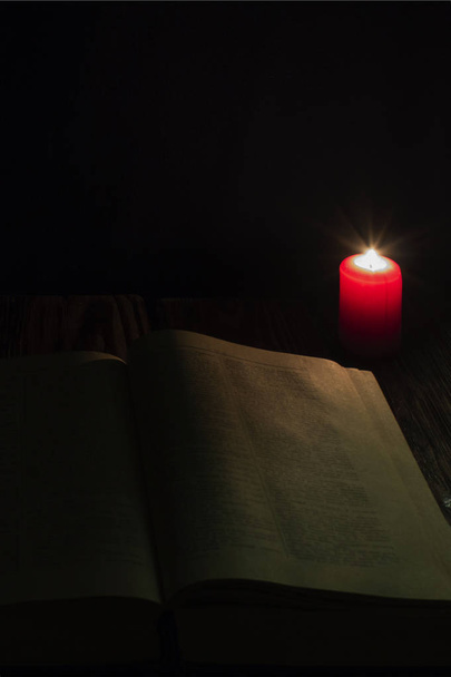 свеча и книга Библии на деревянном фоне ночью
. - Фото, изображение