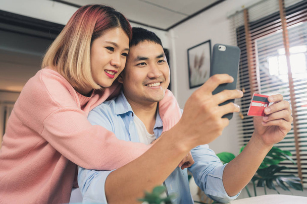 Fiatal ázsiai család pár használ smartphone Hírek megvitatása, vagy csinál online vásárlás elbeszélgettünk íróasztal otthon hétvégén együtt, komoly férfi és nő, böngészés az interneten keres új eladásra kínálja. - Fotó, kép