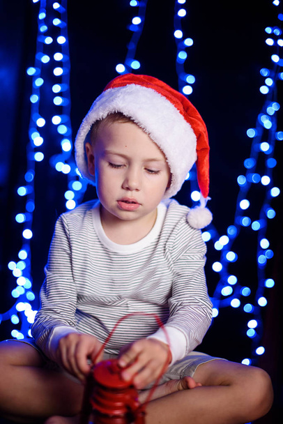 Petit garçon avec un chapeau de Noël et une lanterne. Bokeh de Noël. Nouvel An. Père Noël
 . - Photo, image