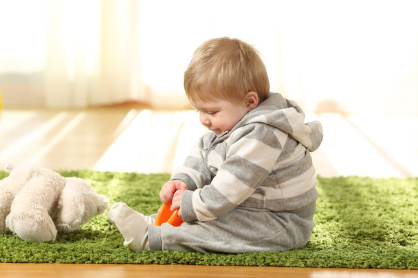 Baby playing alone with toys on a carpet on the floor at home - Φωτογραφία, εικόνα