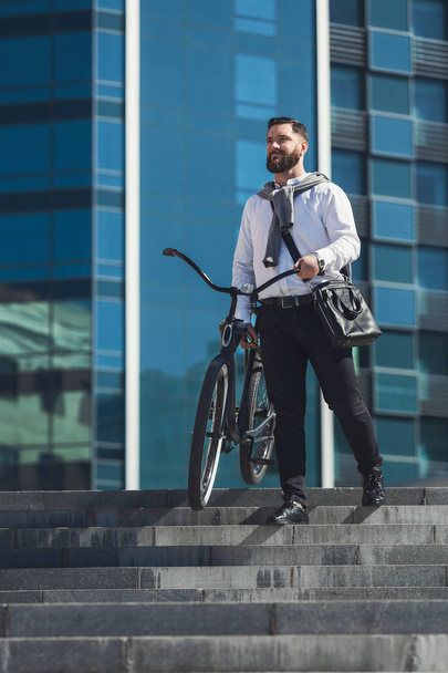 Bearded businessman carrying his bicycle on stairs - Φωτογραφία, εικόνα
