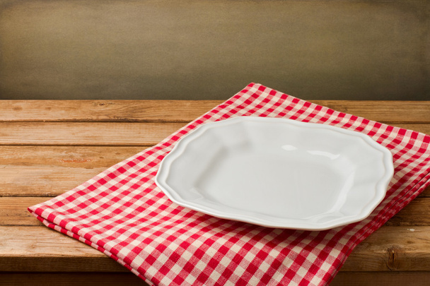 Empty white plate on tablecloth on wooden vintage table - 写真・画像