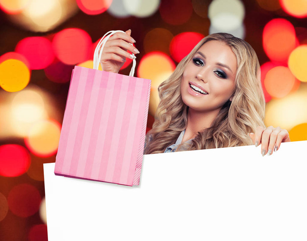 Beautiful woman with shopping bags and white empty board background - Φωτογραφία, εικόνα