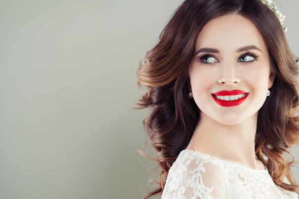 Mujer joven alegre con labios rojos maquillaje y pelo rizado sonriendo. Hermoso retrato de primer plano de cara femenina
 - Foto, Imagen