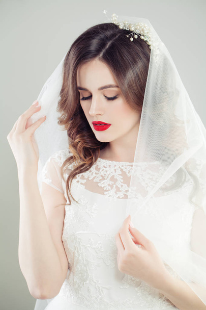 Okouzlující žena nevěsta v bílém závoji na bílém pozadí, módní portrét - Fotografie, Obrázek