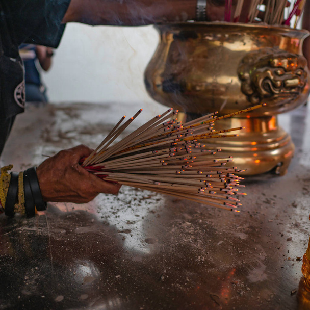 Un montón de Joss quemando palos en la mano en el templo
 - Foto, Imagen