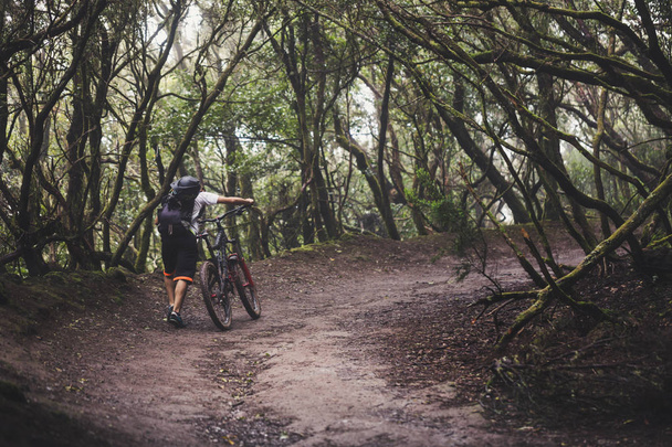 Maastopyöräilijä ohjaa pyörää sademetsässä
. - Valokuva, kuva