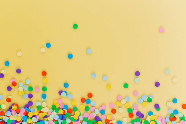 Colorful confetti on yellow background.  - Фото, зображення