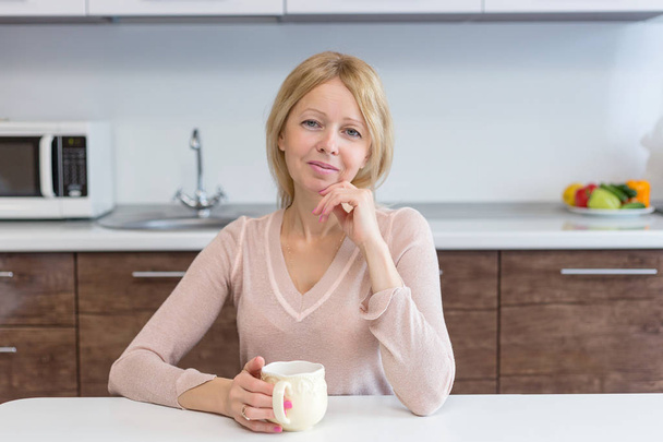 Portrait of an active middle age woman drinking coffee at home - Valokuva, kuva