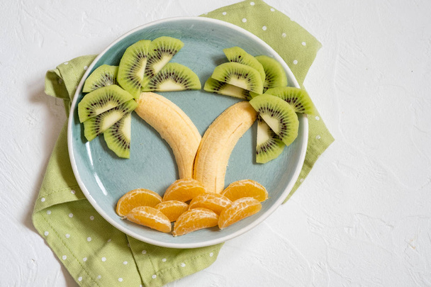 fruit salad for kids, kiwi banana mandarin palm trees - Zdjęcie, obraz