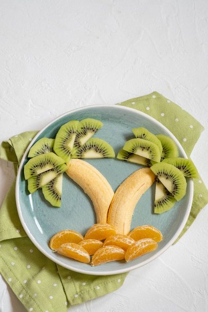 fruit salad for kids, kiwi banana mandarin palm trees - Zdjęcie, obraz