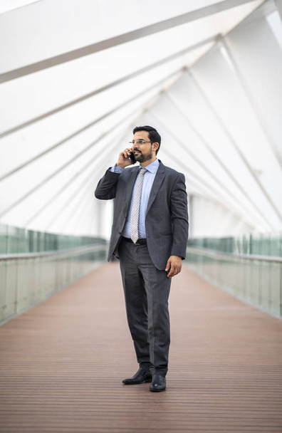 adult confident arab businessman with smartphone on footbridge in emirates - Foto, immagini