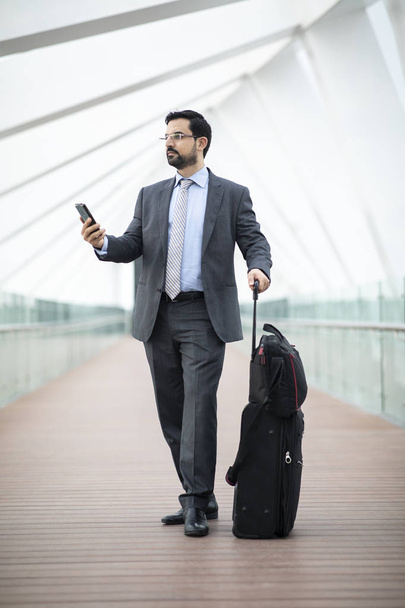 bel homme d'affaires arabe avec smartphone et valise marchant par passerelle
 - Photo, image
