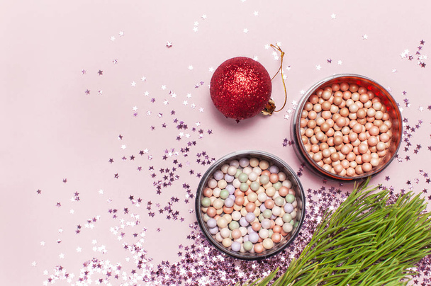 Cosmetic makeup blush, powder, christmas balls, holographic glitter confetti in the form of stars on pink background Flat lay top view copy space. Makeup accessories holiday winter decoration - Fotografie, Obrázek