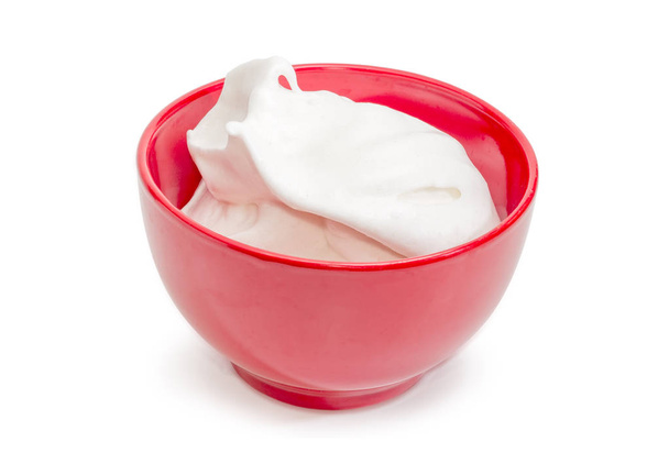 Geslagen eiwit met suiker voor dessert bereiding in de rode keramische kom op een witte achtergrond - Foto, afbeelding