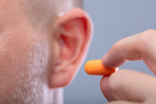 Close-up Of A Man's Hand Inserting Earplug In His Ear - Fotó, kép
