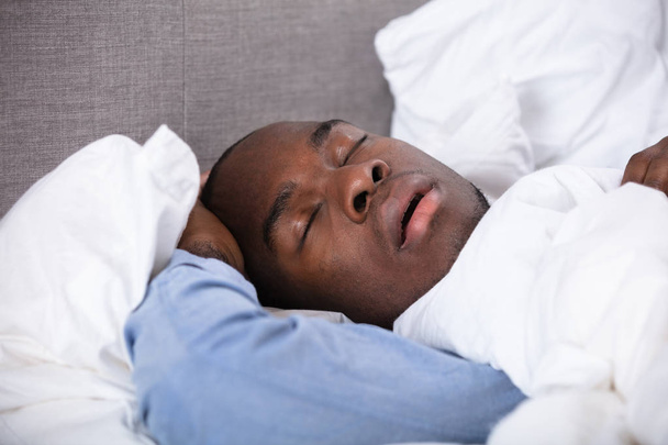 Портрет молодого африканца, спящего на кровати
 - Фото, изображение