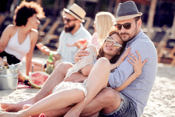Šťastný mladý pár, kteří požívají piknik na pláži a mají dobrý čas na prázdniny. - Fotografie, Obrázek