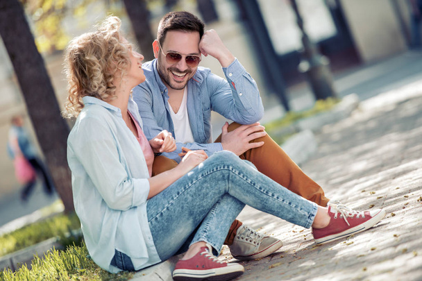 Sonriendo joven pareja hablando y sentados juntos al aire libre
. - Foto, imagen