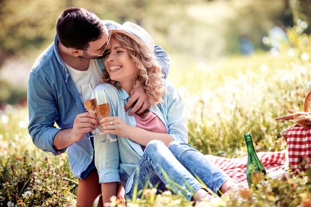 Amor, citas, personas y concepto de celebración - pareja sonriente beber champán en el picnic
 . - Foto, imagen